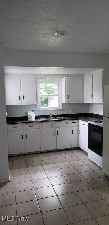 kitchen with dark countertops, electric range, white cabinets, and freestanding refrigerator