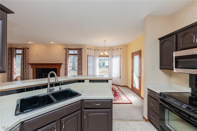 kitchen featuring stainless steel microwave, light countertops, a chandelier, and a sink