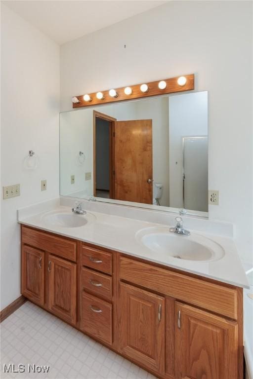 full bath with double vanity, tile patterned floors, and a sink