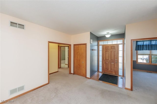 foyer entrance featuring visible vents, baseboards, and carpet flooring