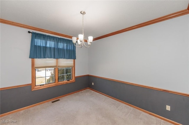 carpeted spare room with visible vents, baseboards, an inviting chandelier, and ornamental molding