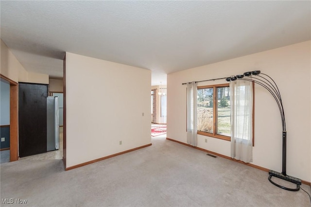 spare room featuring light carpet, visible vents, and baseboards