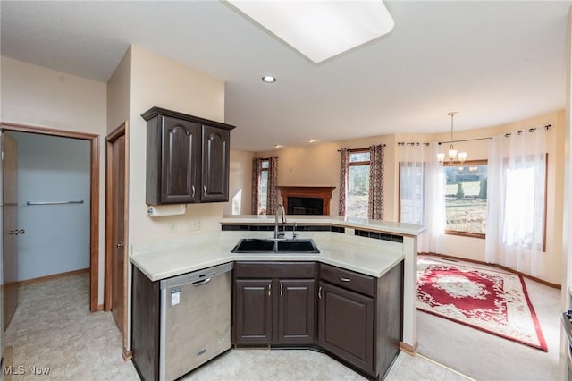 kitchen with a sink, stainless steel dishwasher, dark brown cabinetry, a peninsula, and light countertops