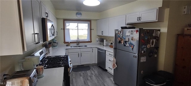 kitchen featuring white cabinets, stainless steel appliances, light countertops, and a sink