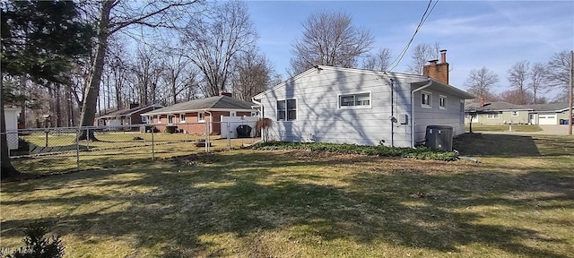 view of side of home with a yard, a chimney, and fence