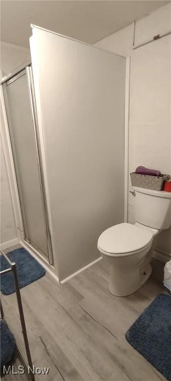 full bath with toilet, wood finished floors, and a stall shower