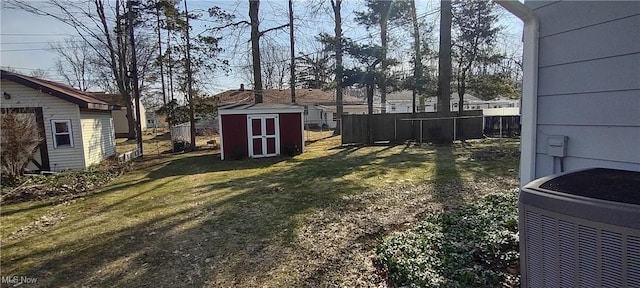 view of yard with central air condition unit, an outbuilding, a storage shed, and fence