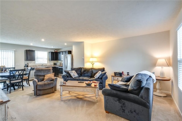 living area with light carpet, recessed lighting, and baseboards