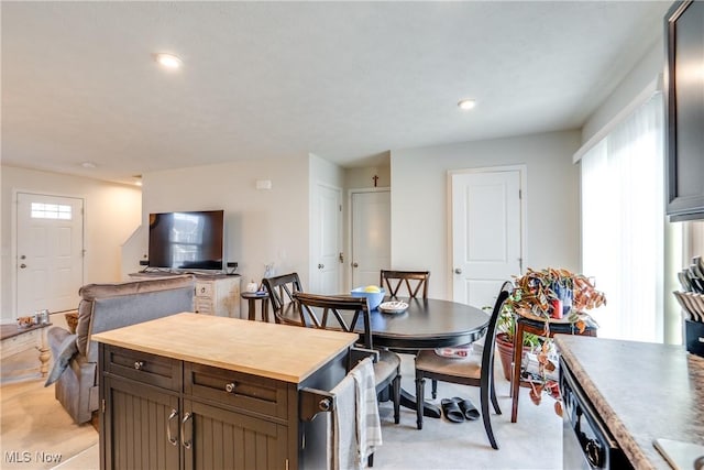 kitchen featuring dark brown cabinetry, recessed lighting, open floor plan, and wooden counters