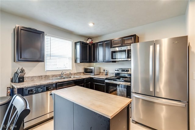 kitchen with butcher block countertops, appliances with stainless steel finishes, a kitchen island, and a sink