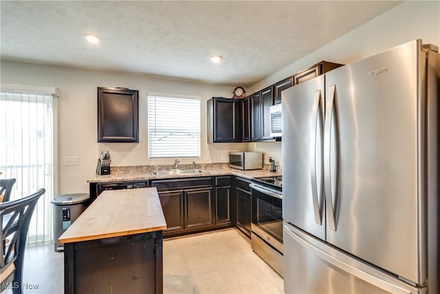 kitchen featuring a sink, dark brown cabinets, butcher block countertops, and stainless steel appliances