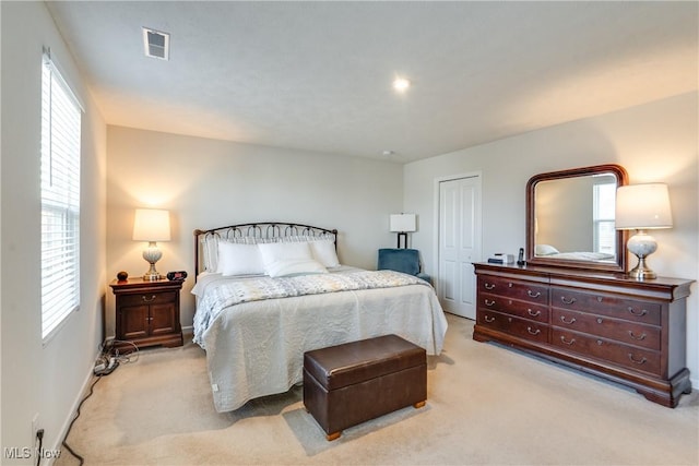 bedroom with visible vents, baseboards, light colored carpet, and a closet