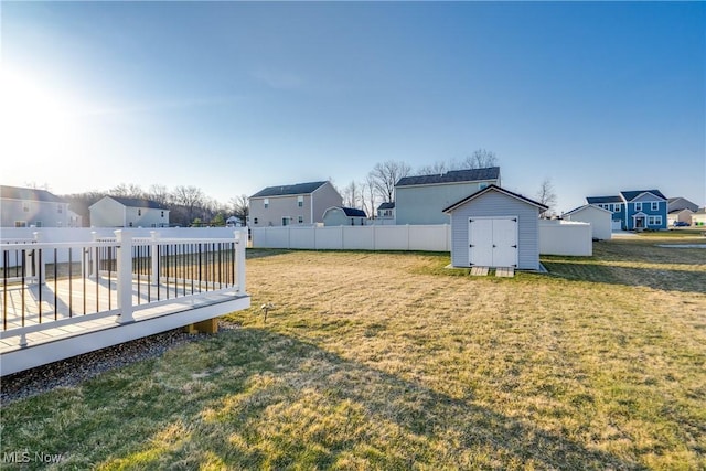 view of yard with a storage unit, a deck, a fenced backyard, a residential view, and an outdoor structure