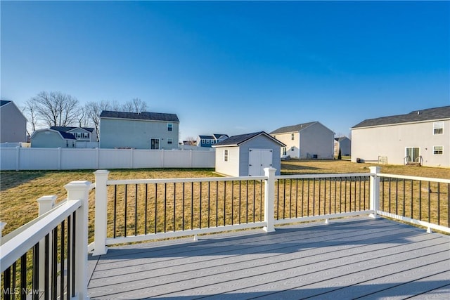 deck featuring fence, an outdoor structure, a storage shed, a lawn, and a residential view