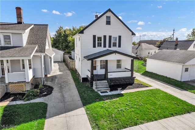 view of front facade featuring a front yard, an outbuilding, driveway, a porch, and a garage