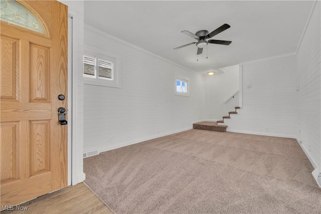 foyer featuring stairway, baseboards, ornamental molding, ceiling fan, and light colored carpet