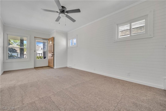 empty room with ceiling fan, ornamental molding, baseboards, and light carpet