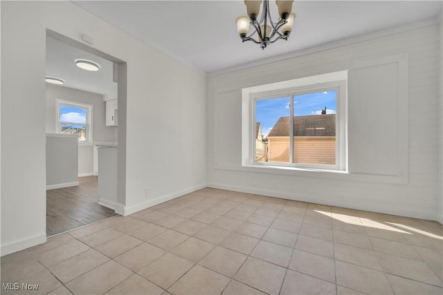 unfurnished room with a wealth of natural light, baseboards, a notable chandelier, and light tile patterned flooring