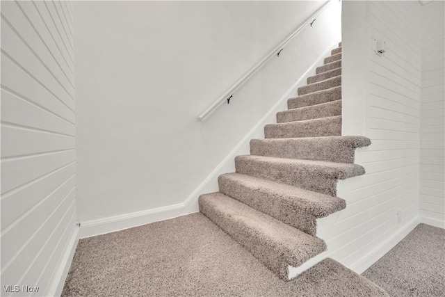 stairway featuring baseboards and carpet