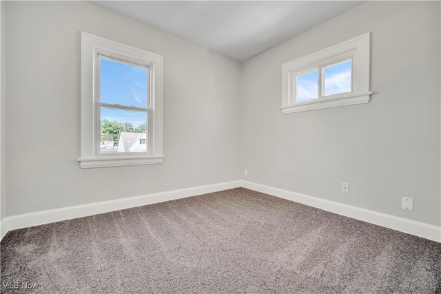 carpeted spare room featuring plenty of natural light and baseboards