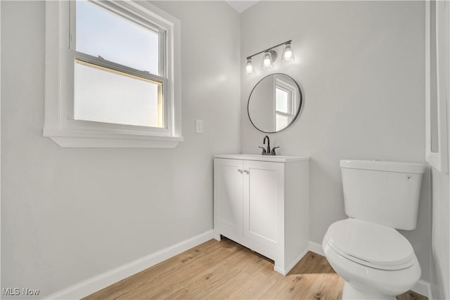 bathroom featuring baseboards, toilet, wood finished floors, and vanity