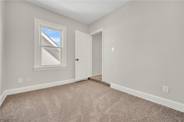 carpeted empty room featuring baseboards