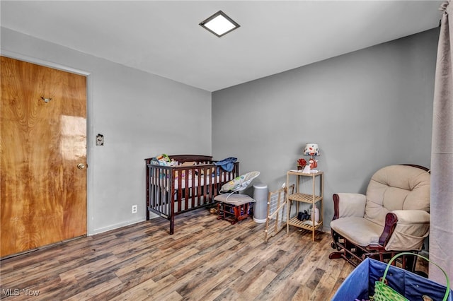 bedroom featuring a crib and wood finished floors