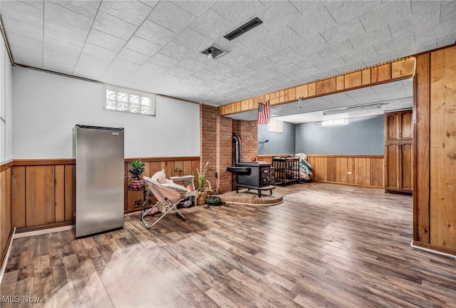 interior space featuring a wood stove, freestanding refrigerator, and wainscoting