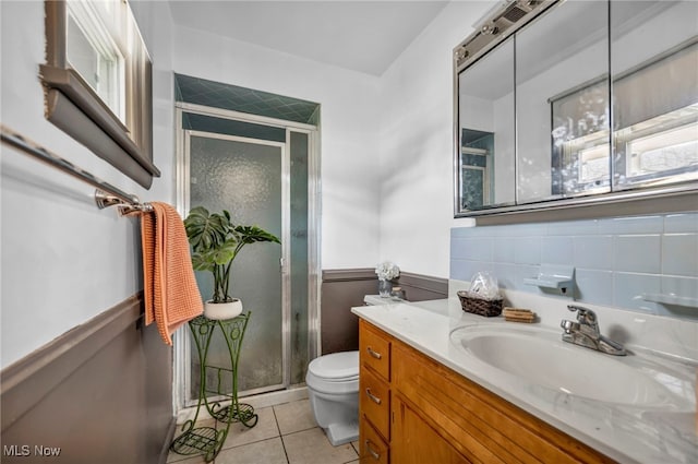 bathroom with vanity, a wainscoted wall, a stall shower, tile patterned floors, and toilet