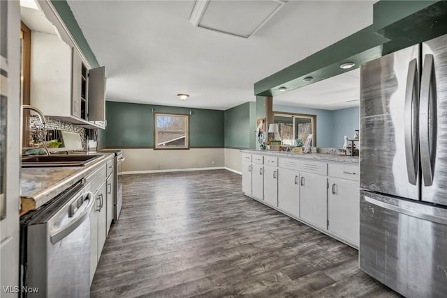 kitchen with dark wood-type flooring, light countertops, white cabinets, stainless steel appliances, and a sink