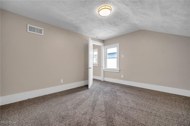 interior space with visible vents, baseboards, a textured ceiling, and lofted ceiling