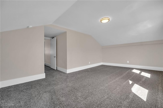 bonus room with baseboards, lofted ceiling, and dark carpet