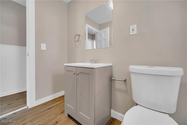 bathroom featuring toilet, vanity, baseboards, and wood finished floors