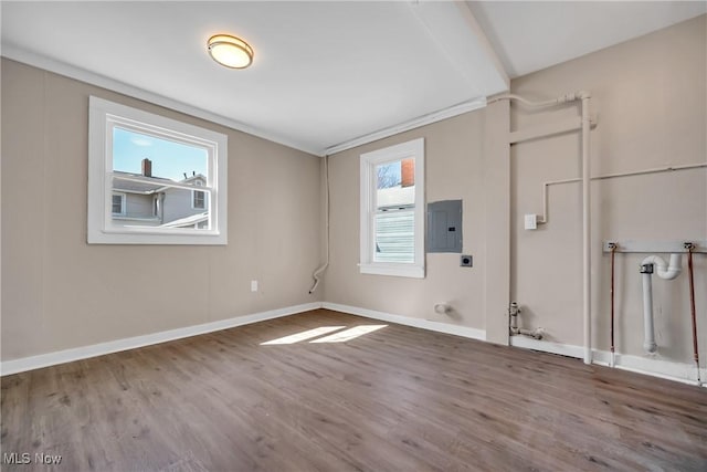 spare room featuring electric panel, baseboards, and wood finished floors