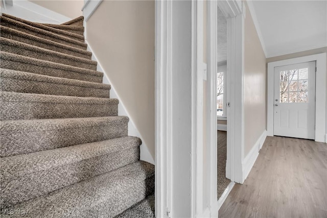 stairs featuring lofted ceiling, baseboards, and wood finished floors