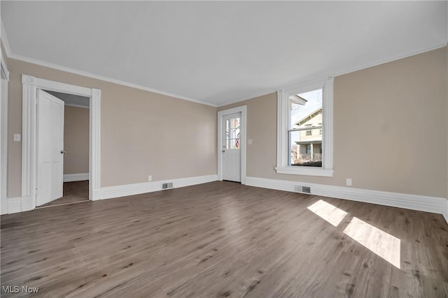 unfurnished living room featuring visible vents, wood finished floors, and ornamental molding