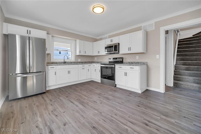 kitchen featuring light stone counters, white cabinets, appliances with stainless steel finishes, and a sink