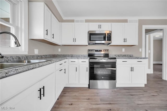 kitchen featuring appliances with stainless steel finishes, white cabinetry, and a sink