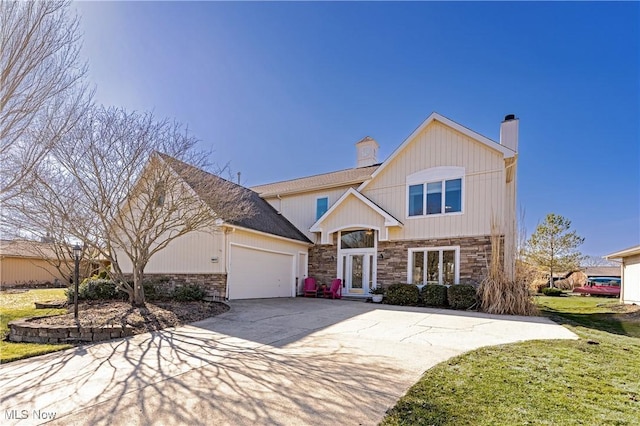 view of front of property with a front lawn, concrete driveway, a chimney, a garage, and stone siding