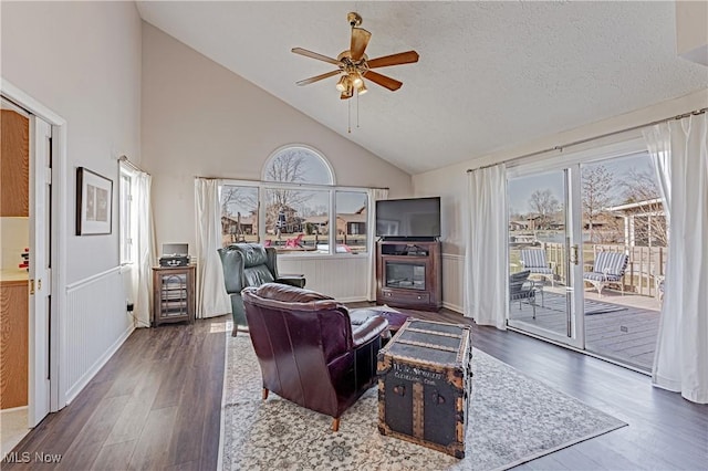 living room featuring plenty of natural light, wood finished floors, a wainscoted wall, and ceiling fan