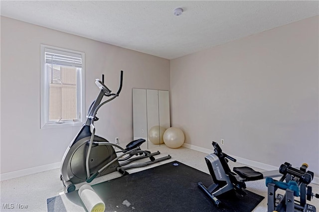 workout area featuring baseboards and a textured ceiling