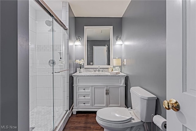 bathroom featuring a stall shower, toilet, vanity, and wood finished floors