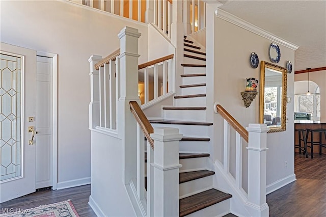 foyer with wood finished floors, baseboards, and ornamental molding