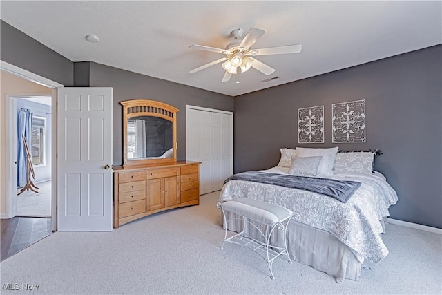 carpeted bedroom featuring a closet, visible vents, baseboards, and ceiling fan