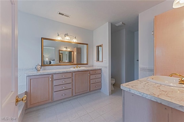 full bath featuring vanity, toilet, and visible vents