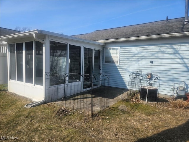 view of side of home with a shingled roof and a sunroom