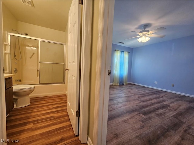 bathroom featuring a ceiling fan, wood finished floors, visible vents, enclosed tub / shower combo, and toilet