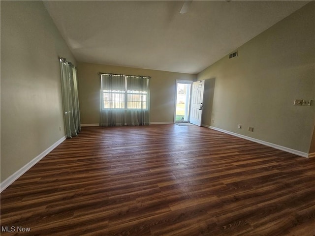 empty room featuring visible vents, baseboards, dark wood-type flooring, and high vaulted ceiling