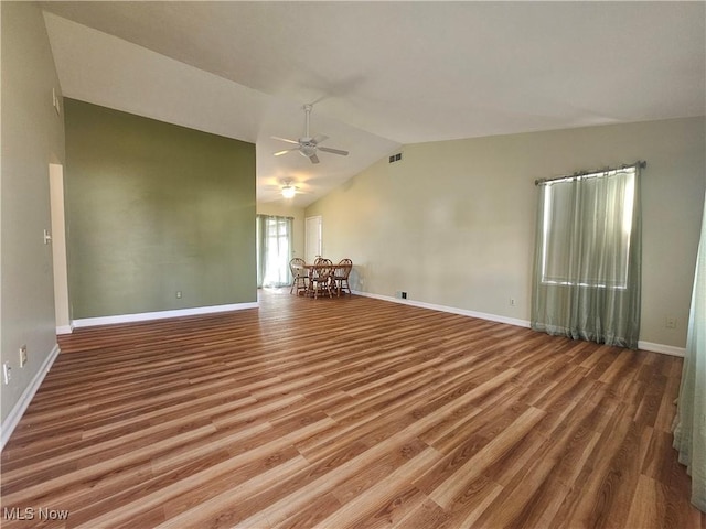 empty room featuring visible vents, wood finished floors, baseboards, ceiling fan, and vaulted ceiling