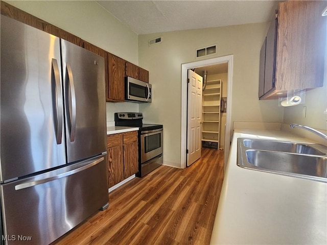 kitchen featuring visible vents, a sink, appliances with stainless steel finishes, light countertops, and vaulted ceiling